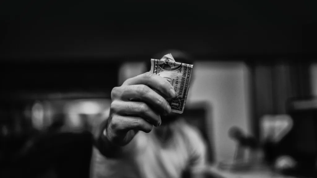 La main d'un homme tenant un billet de 1 dollar